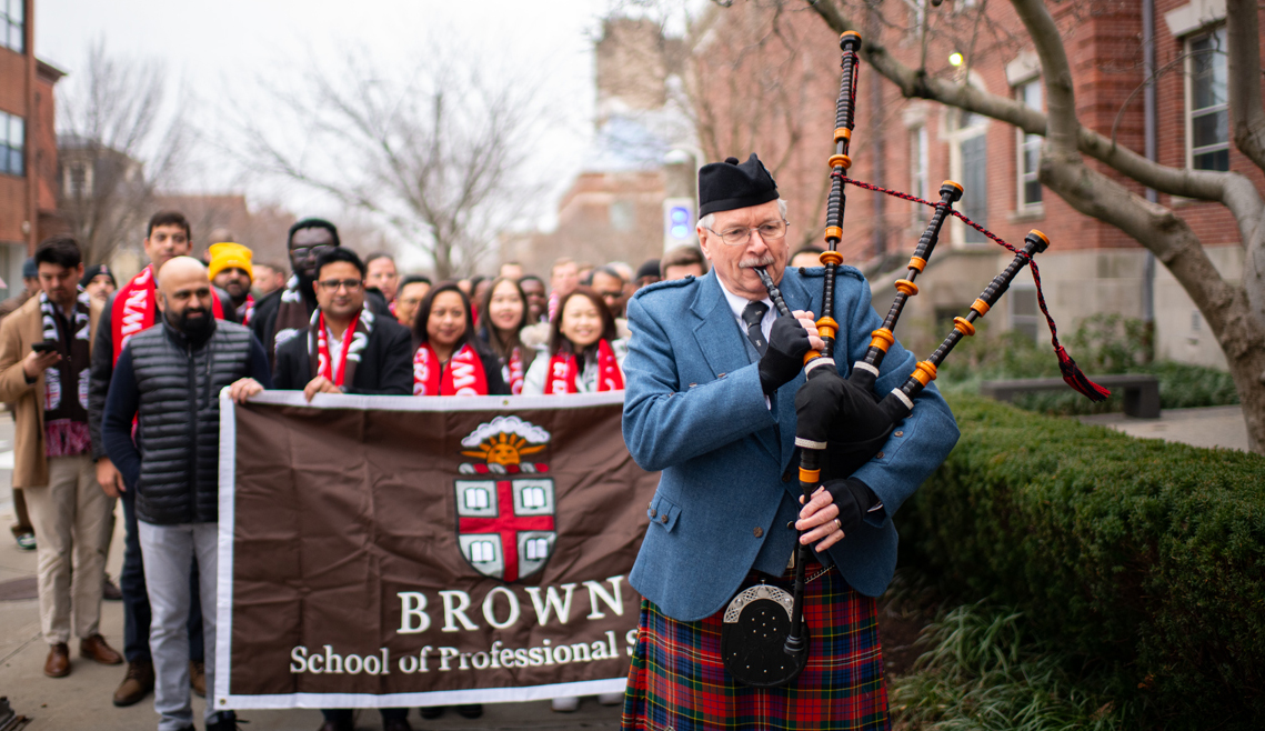 students walking with bagpiper