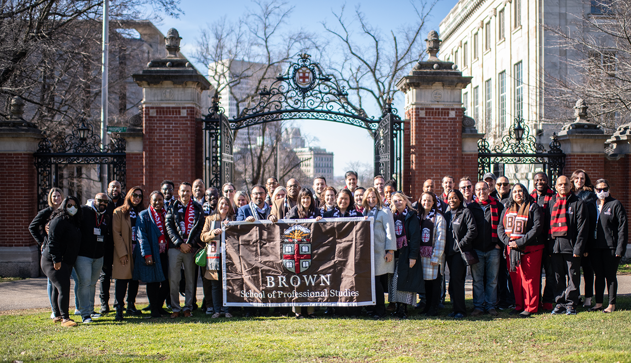 group of students holding a banner in front of gates