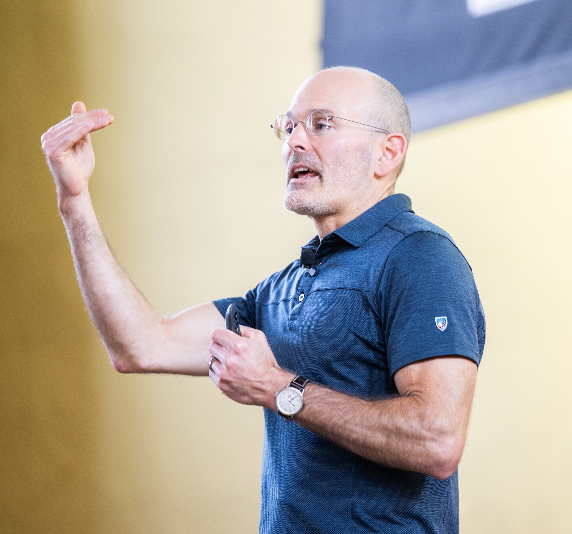 A medium close-up of Dr. Judson Brewer gesturing with his right hand while speaking during a presentation.