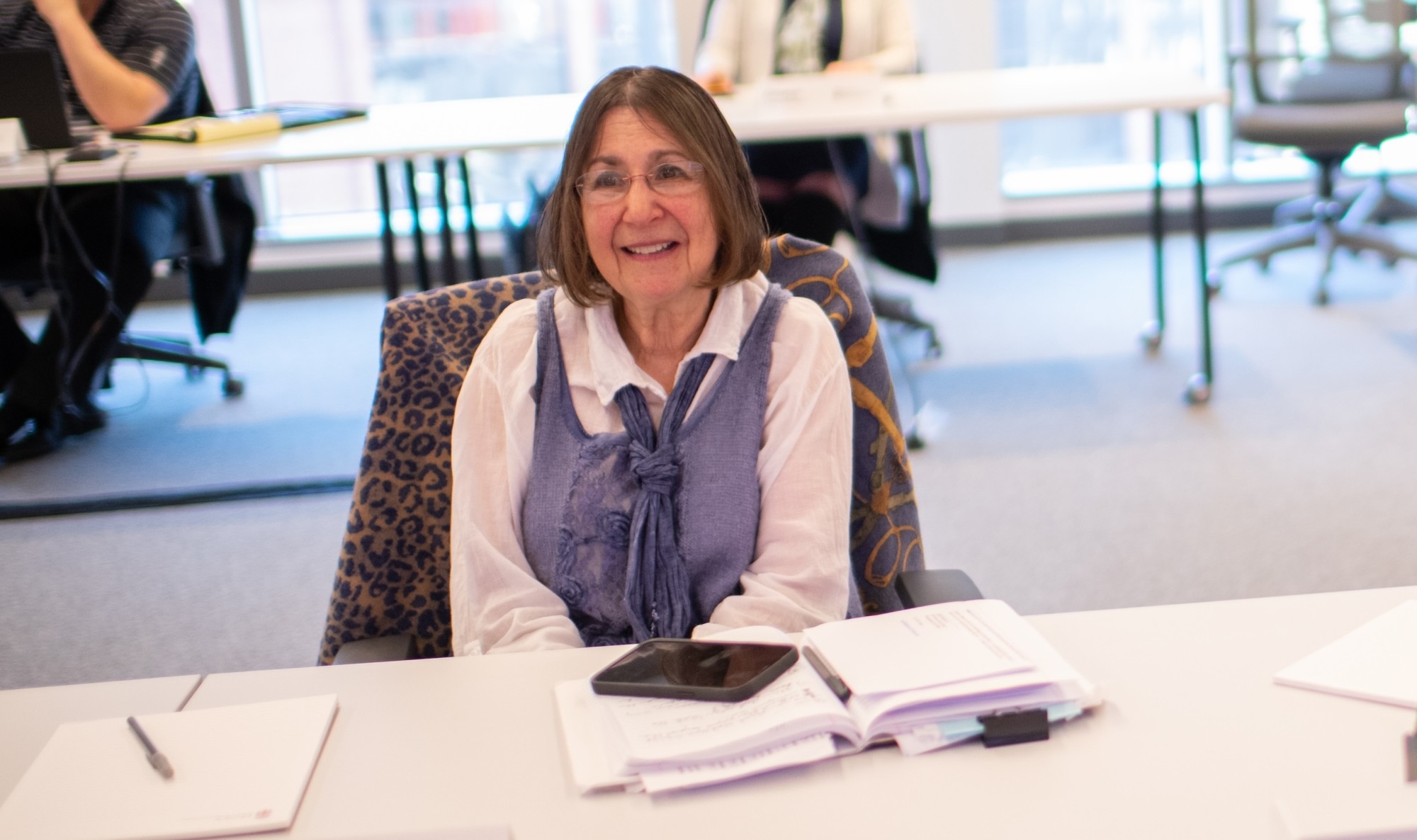 Judith Bentkover sitting in a chair smiling.