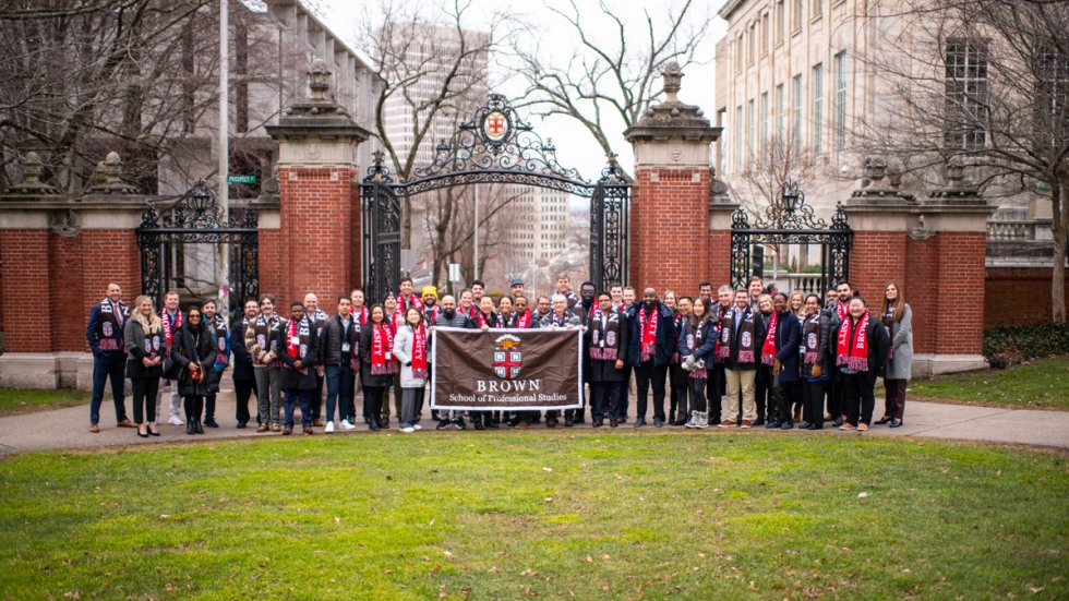 class group photo standing in front of Brown University iconic Van Wickle Gates