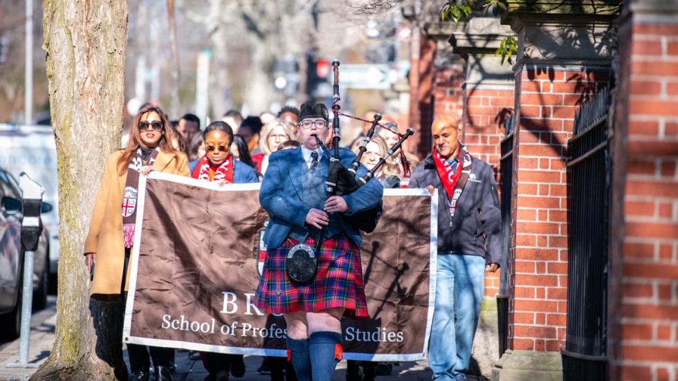 students marching behind bagpiper