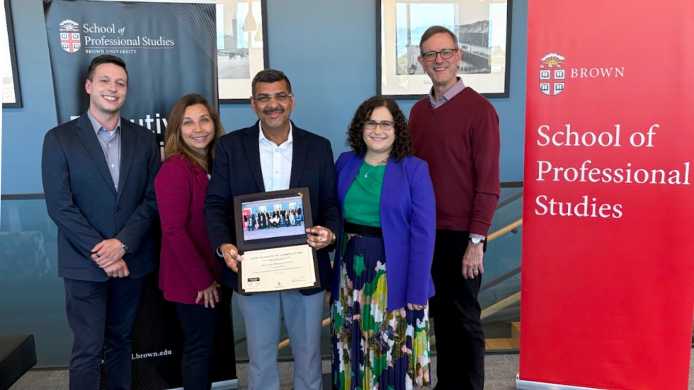 student poses with program leaders for a photo