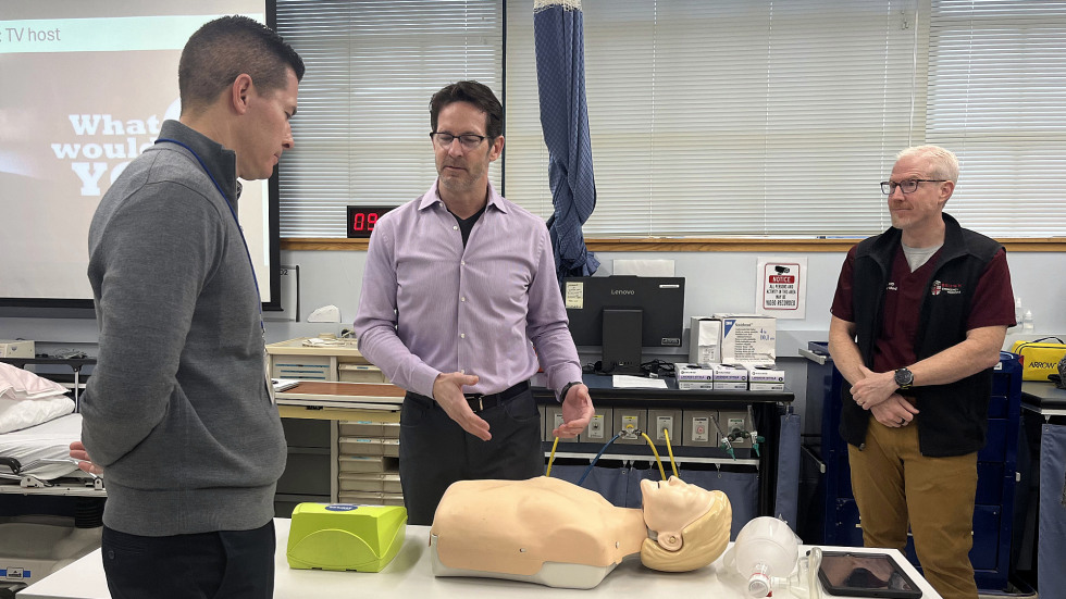 instructor explaining live saving procedure to person on a medical dummy